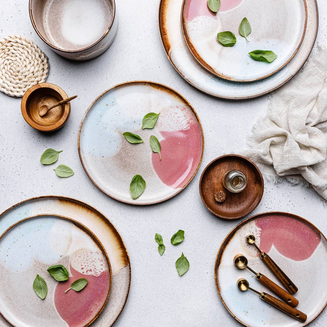 Ceramic plates with pink centers and green leaves on a light gray surface.