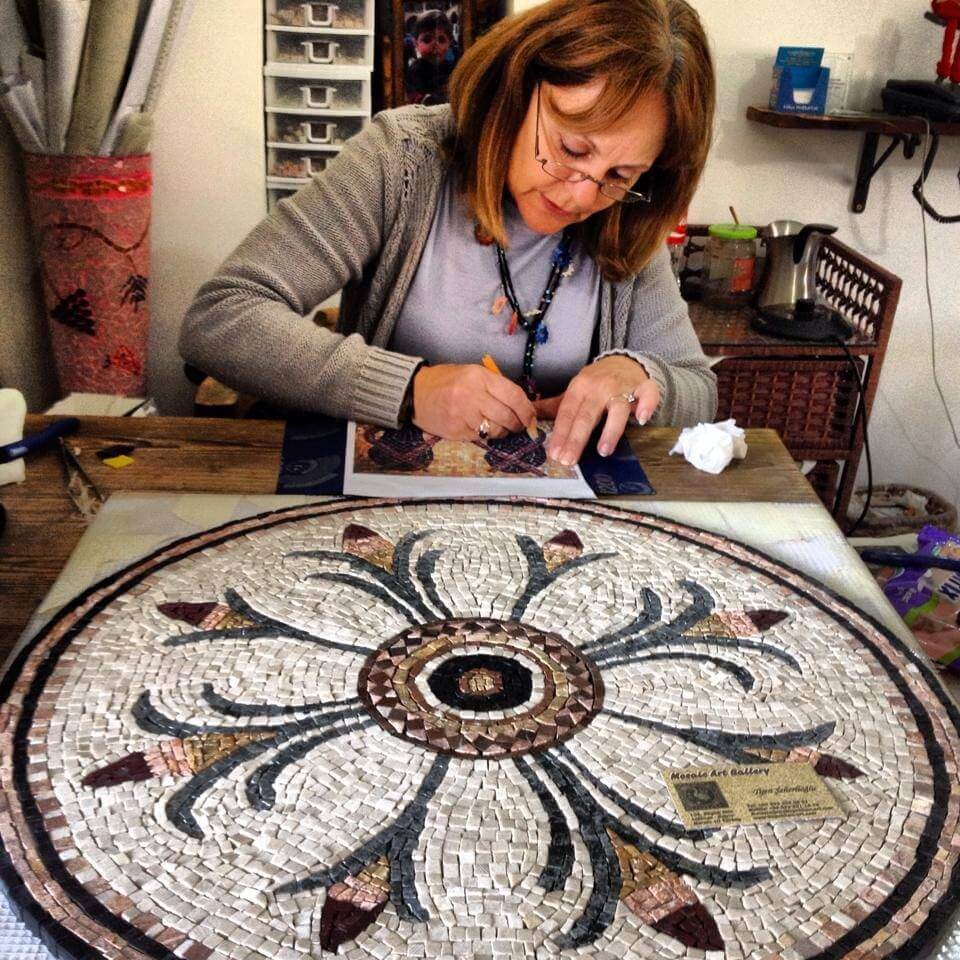 Woman working on a mosaic art project in a workshop.