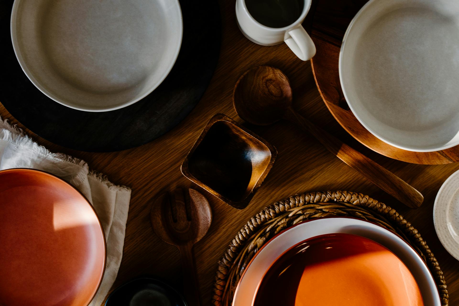 Assorted ceramic plates and bowls on a wooden surface with a focus on color and texture.